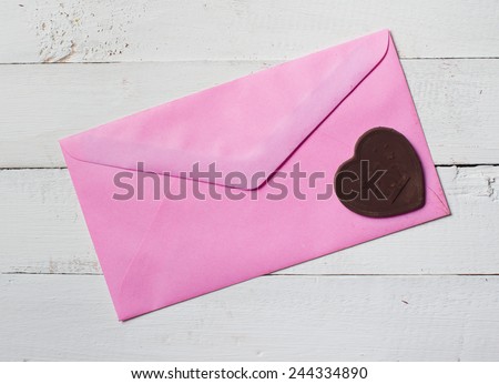 Chocolate heart with letter paper on the wooden background