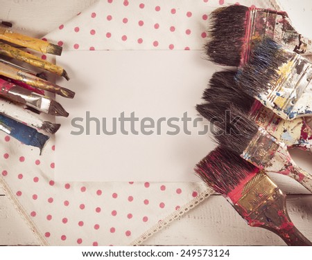 Set of used paint bruches with paper on wood background,vintage color toned image