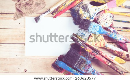 Set of used paint bruches with paper on wood background,vintage color toned image