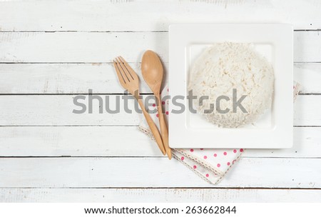 bowl full of rice and spoon on white wood