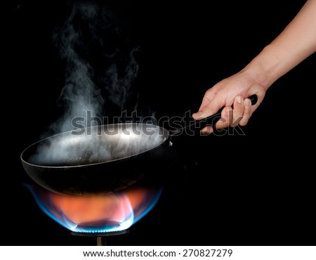 Chef cooking with flame in a frying pan on a kitchen