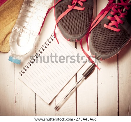 Set for sports activities and notebook on white wooden background,vintage color toned image