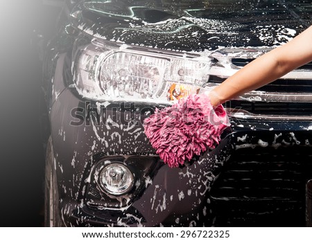 man washing a soapy black car with a cloth