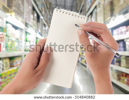 Hand hold blank notepad with space for text,Supermarket blur background