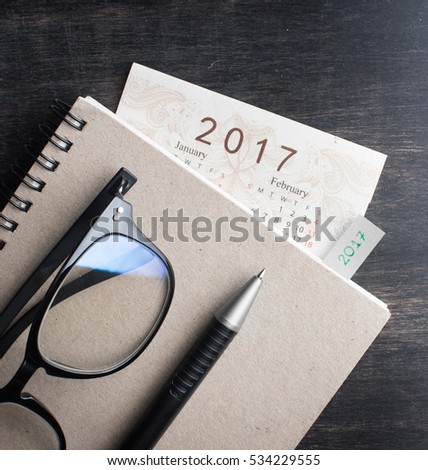 Daily note book with New Year 2017 office organizer calendar on wood table