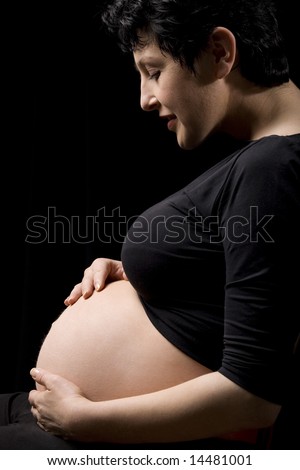 A happy pregnant woman holding her belly with both hands