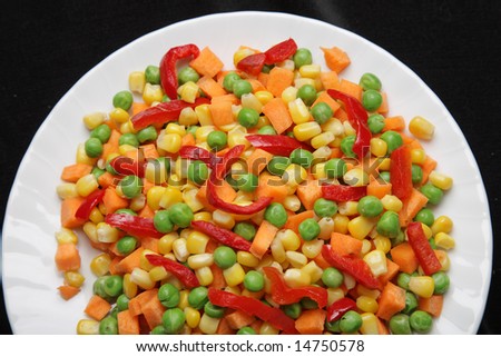 A closeup of a plate with mixed carrots, corn, peas and pepper