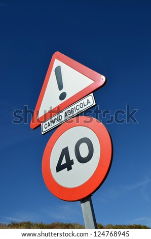 Traffic signs on a rural road with various indications isolated against a blue sky