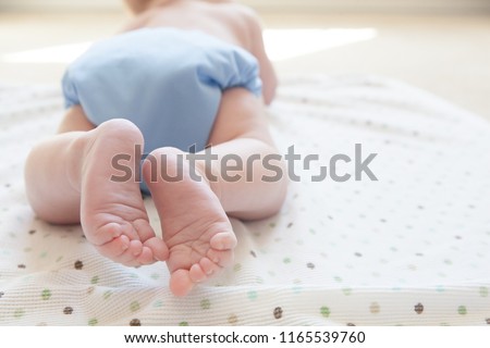 Close up of feet and toes of a baby wearing blue cloth diaper.