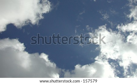 White and light grey clouds against an open patch of medium dark blue sky.