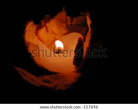 White votive candle burning in orange peel at night.