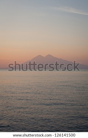 A volcanic island sitting amid the Lesser Sunda Islands near Komodo National Park in Indonesia is silhouetted against early morning glow.  This is part of the ring of fire.