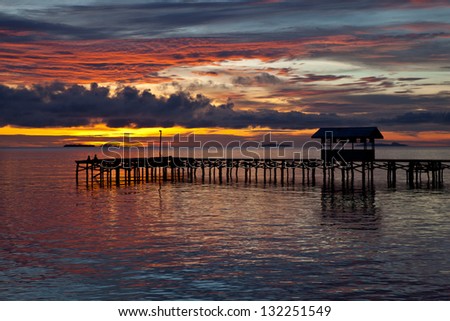 Seen from a Papuan village, the last sunlight of the day lights the clouds above the Dampier Strait in Raja Ampat, Indonesia.  This body of water is full of marine life and offers excellent diving.