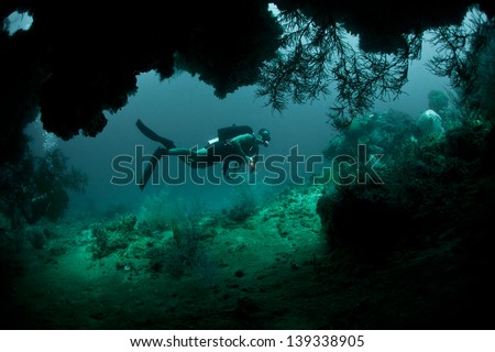 A Diver Explores The Mouth Of A Deep Cave In Raja Ampat, Indonesia. This Area Is Known For Its High Marine Diversity And Great Scuba Diving.