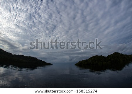 Early morning light illuminates clouds above a set of islands near the Dampier Strait in Raja Ampat, Indonesia. This region is known for its extraordinary marine diversity and great scuba diving.