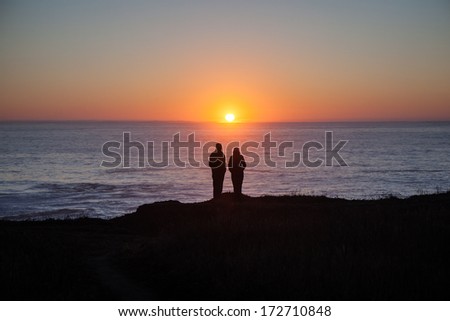 A couple enjoys the sunset from the cliffs of Mendocino, California. This part of northern California has a rugged, yet idyllic coastal setting and is accessible by Highway 1.