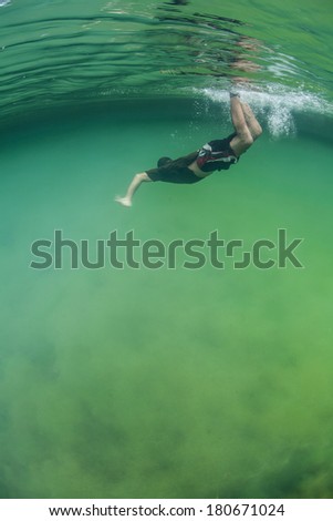 A snorkeler dives into an isolated marine lake filled with algae in Raja Ampat, Indonesia. Marine lakes, found in limestone areas, are filled with seawater but are not directly connected to the ocean.