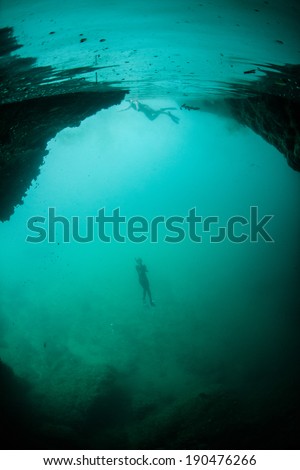 A free diver ascends at the mouth of an underwater cave in Raja Ampat, Indonesia.