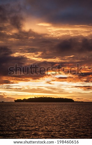 A brilliantly colored sunrise greets a remote island in the Solomon Islands. This region is within the Coral Triangle and is known for its high marine biological diversity and beautiful scuba diving.
