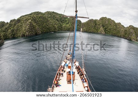An Indonesian Pinisi schooner sails near a set of high limestone islands near Misool in Raja Ampat, Indonesia. This region offers spectacular scuba diving and snorkeling.