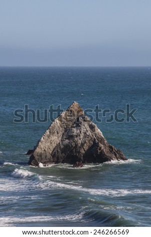 Pacific ocean waves wash against a sea stack off the coast of California. Wave energy has helped shape the shoreline of the entire west coast.
