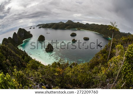 Clouds cover a gorgeous tropical lagoon in Wayag, Raja Ampat, Indonesia. This remote area near the equator is a maze of rugged limestone islands and coral reefs.