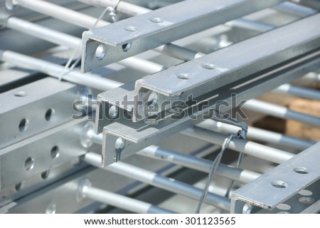 Galvanized steel tower ladder bundle in industrial stockyard.