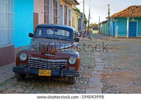 Trinidad, Cuba - November 05, 2012: Vintage car parked on the street with people in the background