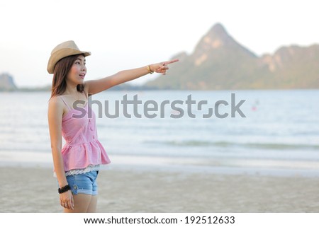 Beach woman pointing showing vacation concept. Beautiful happy summer on tropical beach holidays travel pointing happy smiling at copy space.