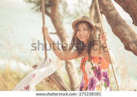 Beautiful woman sitting on rope swings on the beach. Samed island, Thailand