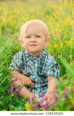 funny boy sitting in a field with flowers