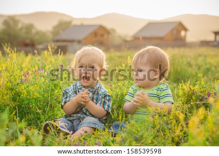 two funny boy sitting in a field with flowers