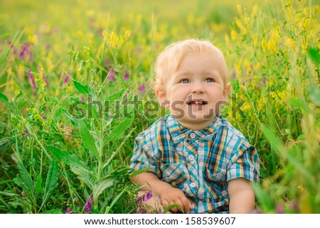 funny boy sitting in a field with flowers