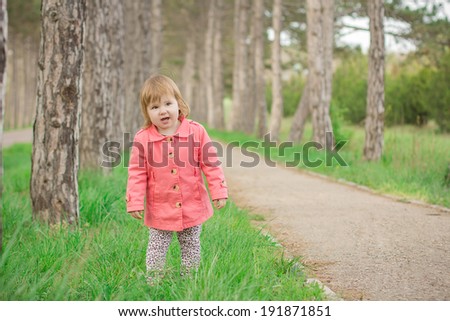 funny girl in a pink coat standing in the park