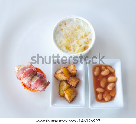 Omelette,scrambled eggs with pork sausage & bacon on white plate