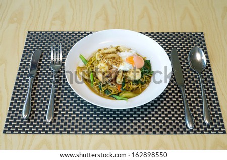 fried noodles with sea food, vegetables and poached egg, thai food
