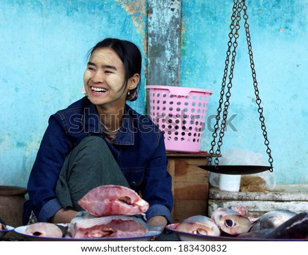 BAGAN, MYANMAR- JANUARY 4: A fishmonger sell some fishes with traditional scales in the wet market on January 4, 2011 in bagan Market,Myanmar. The traditional Asian wet market still exist in myanmar.