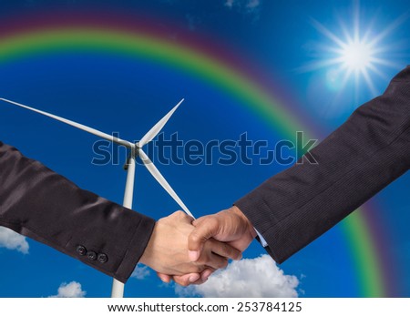Hand shake between a businessman on Wind turbine power generator background