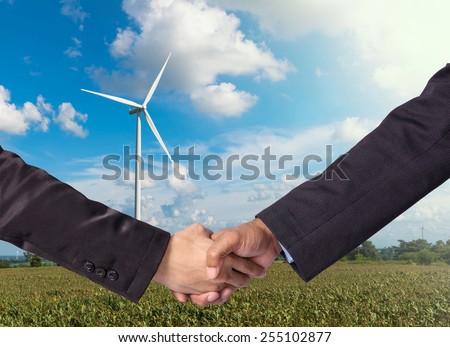 Hand shake between a businessman on Wind turbine power generator background