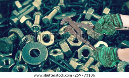 two hands holding the adjust spanner on used nut and bolts for equipment industrial background