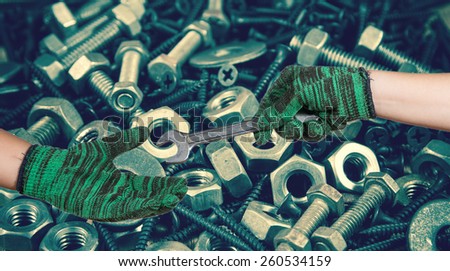 hand holding the wrench on used nut and bolts for equipment industrial background