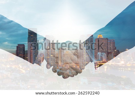 double exposure handshake between businessman on a city background