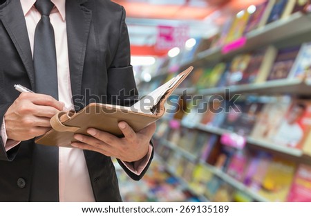 Businessman writing the note book on Abstract blurred photo of book store background