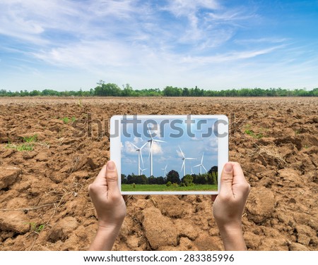 Female hands holding tablet taking pictures Wind turbine power generator on blue sky, industry concept