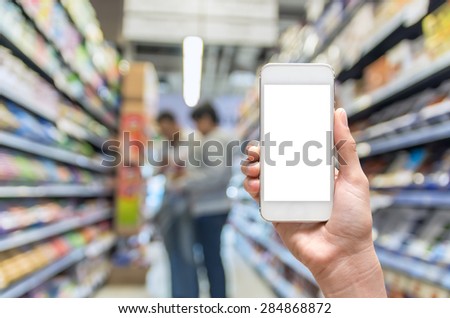 Female hand holding mobile smart phone on Supermarket blur background, business concept