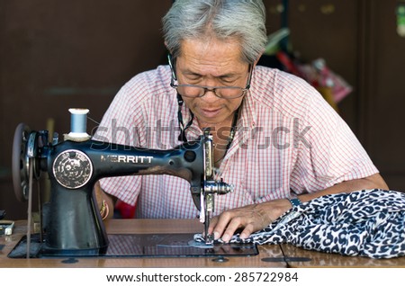 BANGKOK, THAILAND - JUNE 04: Asian old man Seamstress are sewing the clothes by vintage sewing machine on June 04, 2015 at bangkok, Thailand
