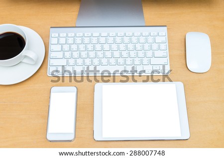 Workplace, computer, tablet, smart phone, key board and coffee cup on wooden table