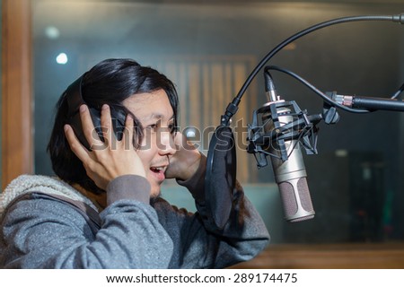 Young Asian singer recording a song with microphone in music studio