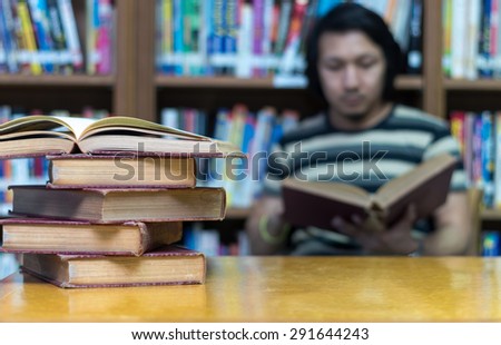 old book on the desk in library with the man reading the book background