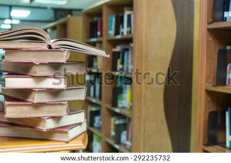 stack of old book on the desk in library blur background